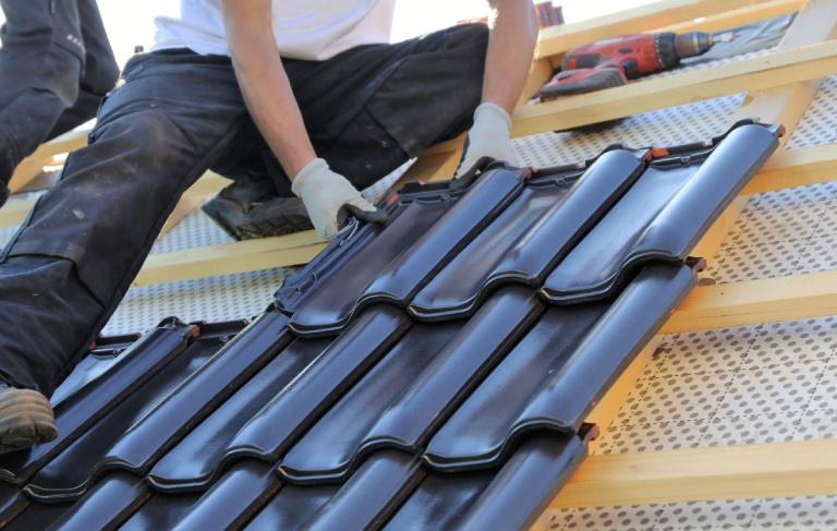 Pracownik montuje pokrycie dachowe